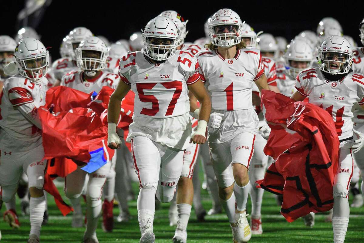 Greenwich's David Nasimi (57) leads the charge onto the field at the start of the CIAC Class LL Football Quarterfinals against Darien at Darien High School in December 2019.