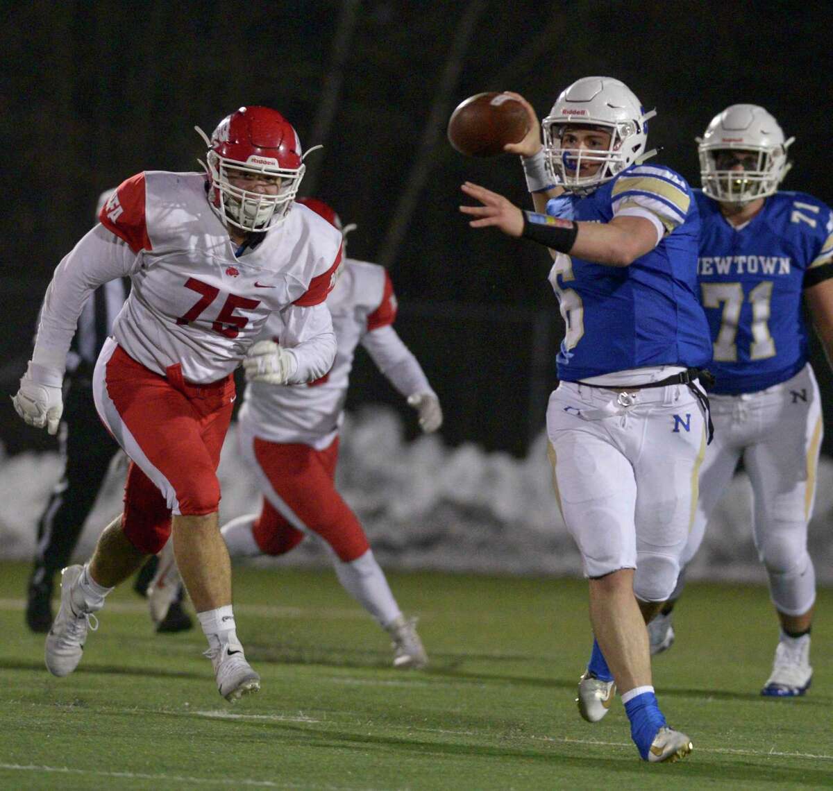 Newtown quarterback Brandon Lombardo (6) looks to throw while being chased by NFA's Joshua Brown (75) in the Class LL State Football Quarterfinal game between No.8 Norwich Free Academy and No. 1 Newtown high schools, Wednesday December 4, 2019, at Newtown High School, Newtown, Conn.