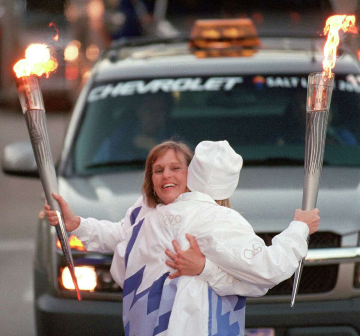 Donna Plewa-Allen of Katy, left, hugs Dana Walker, also of Katy, as they exchange the Olympic flame Dec. 10, 2001 along Post Oak. The pair were part of the 2002 Olympic Torch Relay, which carried the torch to Salt Lake City for the Winter Games.