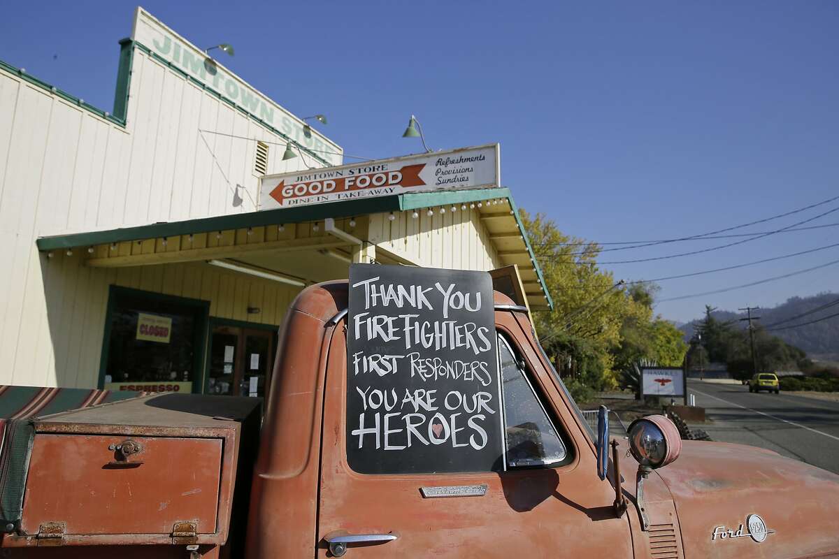 In this Wednesday, Nov. 6, 2019 photo, a sign thanking firefighters is displayed on the historic truck outside the Jimtown Store in Healdsburg, Calif. Tourism, which is usually booming amid the fall colors and mild temperatures, has taken a blow. Evacuations of nearby Healdsburg and Windsor, along with planned blackouts by the region's utility, PG&E, plus, the widespread misperception that the vineyards themselves burned have led to a rash of cancellations for hotel, restaurant and tasting-room reservations. (AP Photo/Eric Risberg)