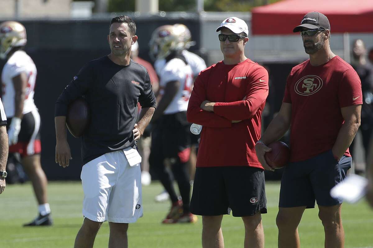 San Francisco 49ers head coach Kyle Shanahan, from left, watches as players practice with general manager John Lynch and broadcaster Tim Ryan at the team's NFL football training camp in Santa Clara, Calif., Saturday, July 27, 2019. (AP Photo/Jeff Chiu)