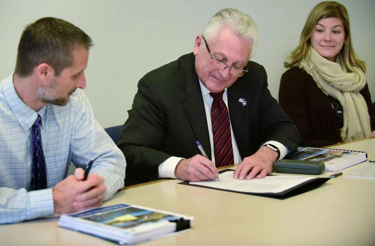 Norwalk Mayor Harry Rilling, center, signs the city's new Plan of Conservation and Development with Planning and Zoning Director Steve Kleppin, left, Norwalk Chief of Economic and Community Development, Jessica Casey, right, and the rest of the POCD committee including Planning and Zoning Director Steven Kleppin, left, Thursday, December 5, 2019, at City Hall in Norwalk, Conn. The plan will guide development in the city from 2019 to 2029.