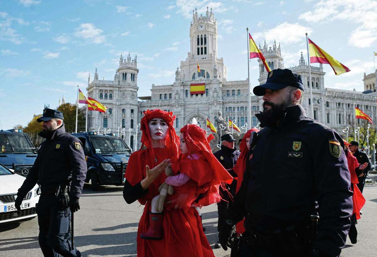Police officers walk beside global environmental movement Extinction Rebellion activists during a protest at the Cibeles square in Madrid, on December 3, 2019. - Spain's Socialist government offered to host this year's UN climate conference, known as COP25, from December 2 to December 13, 2019, after the event's original host Chile withdrew last month due to deadly riots over economic inequality. (Photo by OSCAR DEL POZO / AFP) (Photo by OSCAR DEL POZO/AFP via Getty Images)