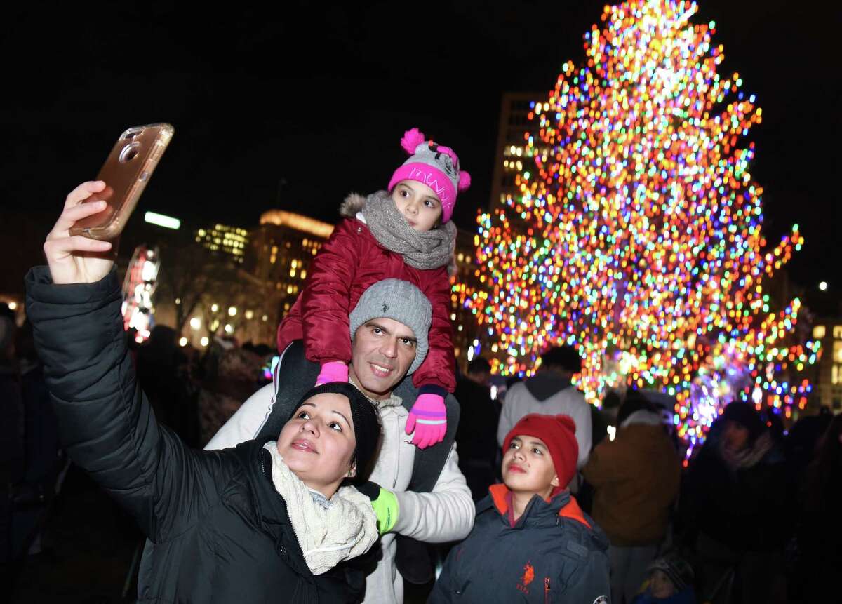 Marly Rodriguez (left) of New Haven takes a selfie with her husband, Victor, daughter, Marlin, 7, and son, Victor David, 11, in front of the Christmas tree on the New Haven Green after the tree lighting on December 5, 2019.