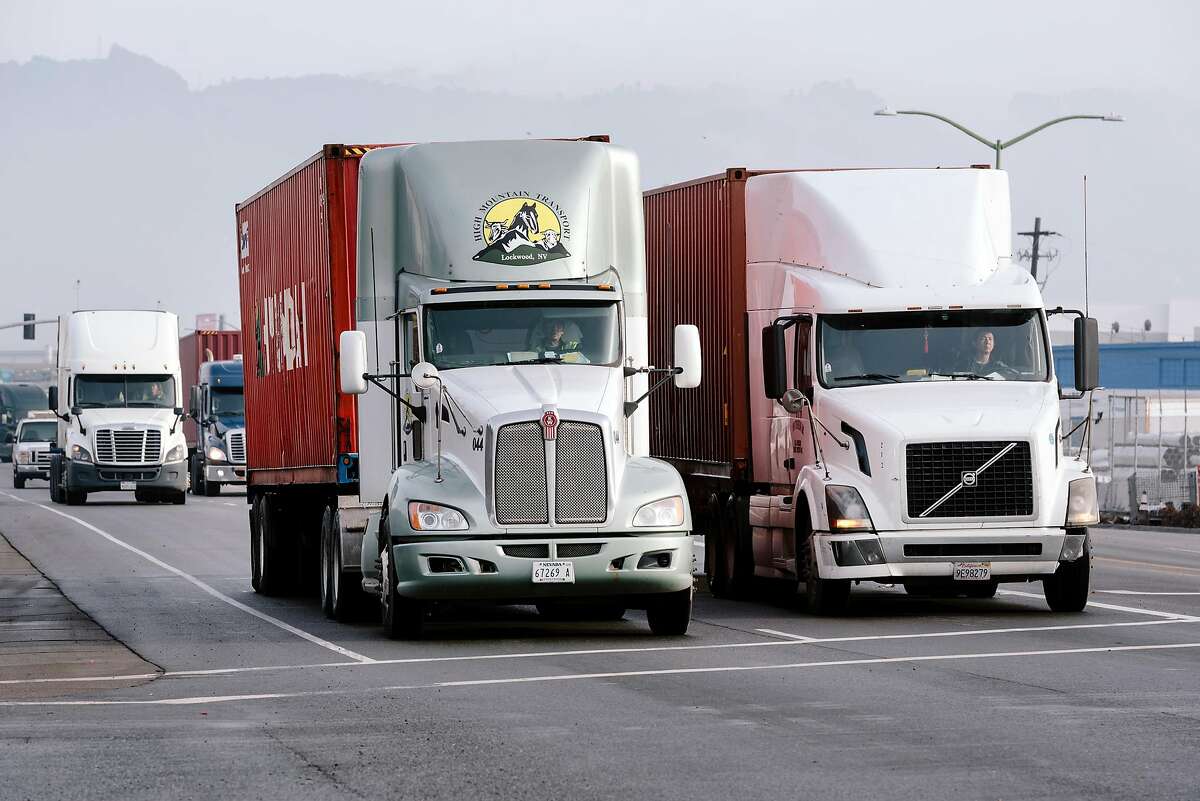 Trucks move through the Port of Oakland late last year. A state appeals court has ruled truckers in California can be classified as employees under state law.