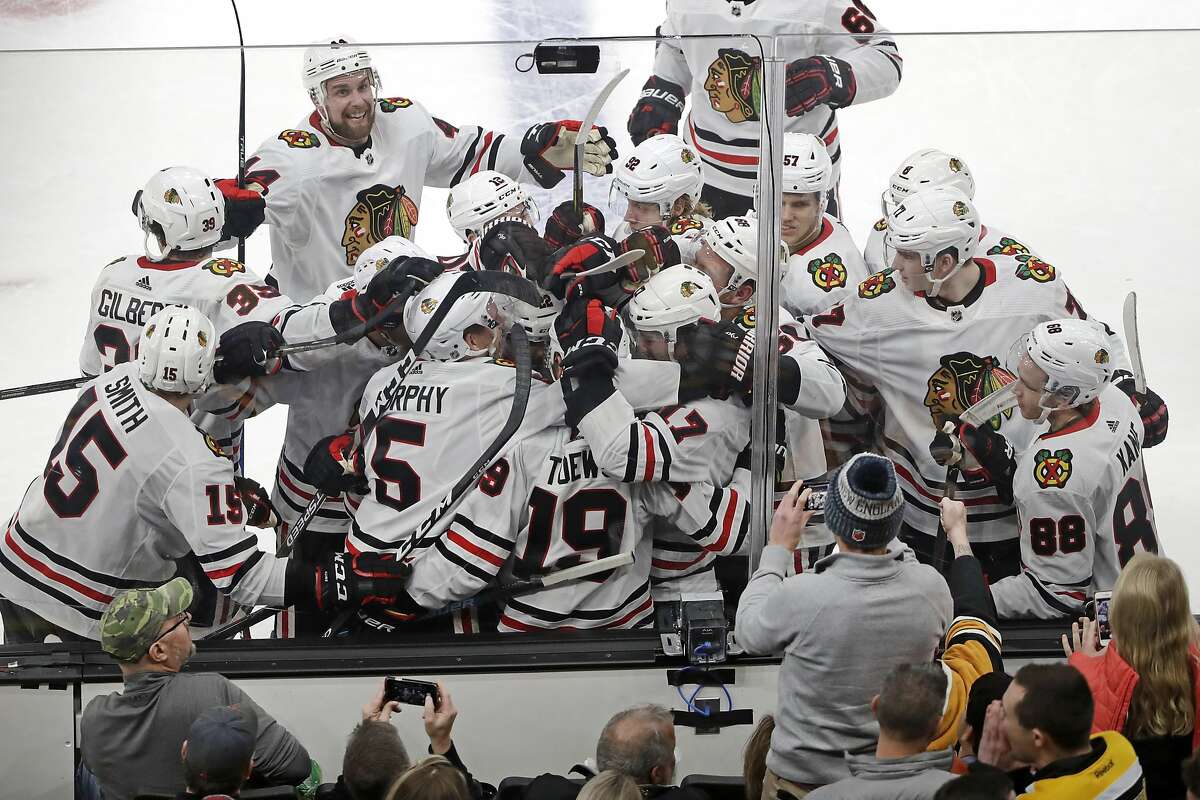 Chicago Blackhawks players mob Jonathan Toews (19) as they celebrate his game-winning goal against the Boston Bruins in the overtime period of an NHL hockey game, Thursday, Dec. 5, 2019, in Boston. The Blackhawks won 4-3 in overtime. (AP Photo/Elise Amendola)