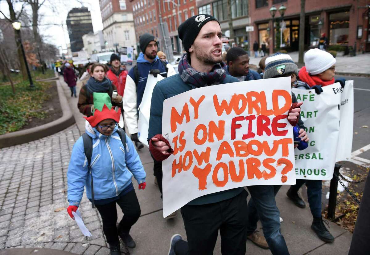 Christopher Ewell (center) of New Haven participates in a climate strike as it travels up Chapel Street in New Haven on December 6, 2019.