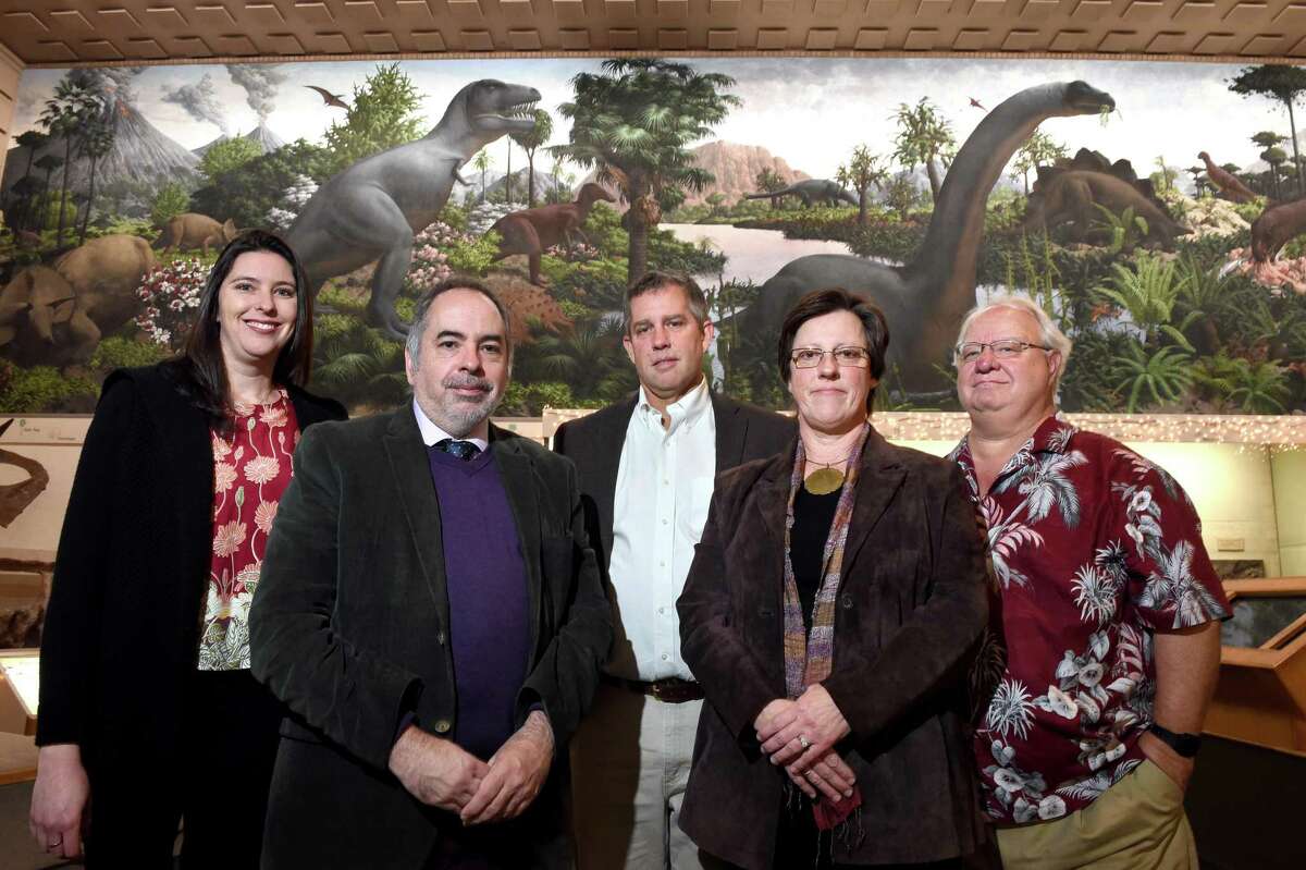 From left, Vanessa Rhue, Collection Manager, Vertebrate Paleontology, Christopher Norris, Director of Public Programs, Director David Skelly, Carol Denatale, Project Director and Tim White, Director of Collections & Research are photographed in the Great Hall of Dinosaurs at the Yale Peabody Museum of Natural History Dec. 4, 2019. In the background is a section of The Age of Reptiles mural by Rudolph Franz Zallinger.