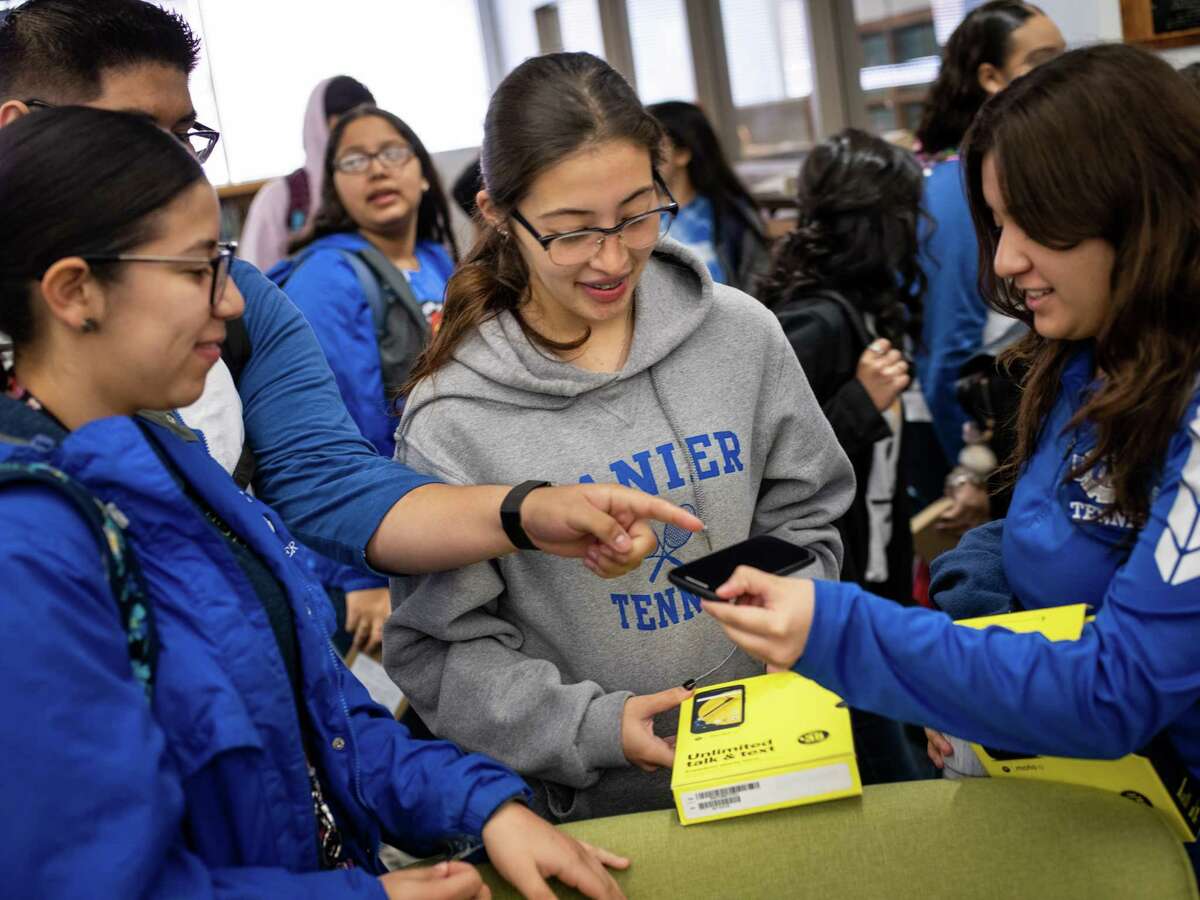 From left, Emily Rocha, Klarise Rico and Genesis Martinez look at the free smart phone that Rico received at Lanier High School on Friday. SAISD partnered with 1Million Project Foundation to supply 5,200 high school students throughout the district with free wireless connectivity via smart phones or hotspot devices for their homes.