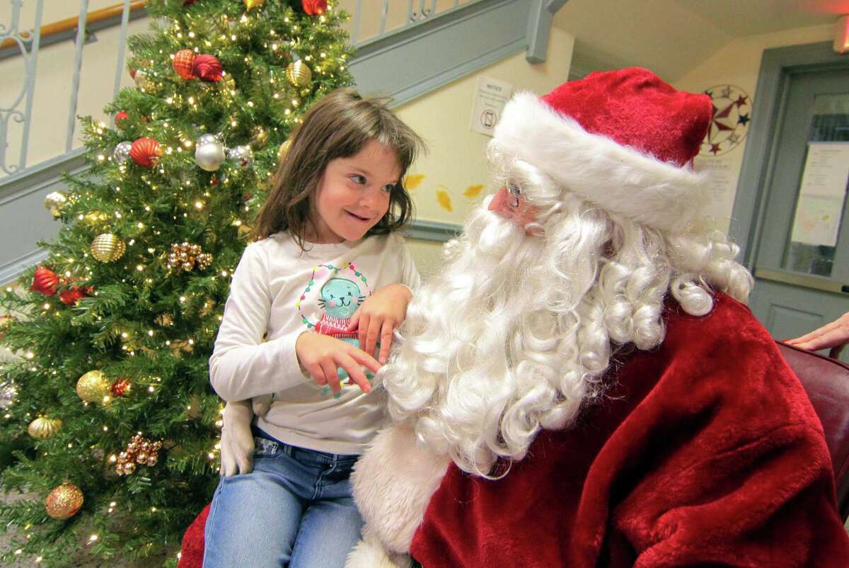 Mary Capriotti, 5, of Shelton, tells Santa what she wants for Christmas during the annual holiday tree lighting event at Town Hall Green in Trumbull, Conn., on Friday Dec. 6, 2019.
