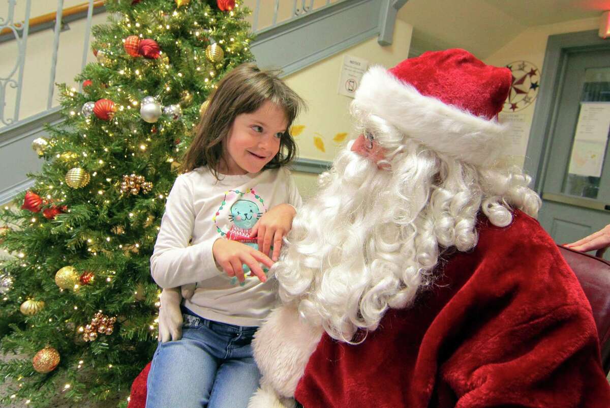 Mary Capriotti, 5, of Shelton, tells Santa what she wants for Christmas during the annual holiday tree lighting event at Town Hall Green in Trumbull, Conn., on Friday Dec. 6, 2019.