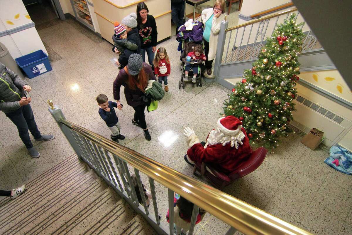 Alicia Curria guides her son Luca 2, towards Santa to tell him what he wants for Christmas during the annual holiday tree lighting event at Town Hall Green in Trumbull, Conn., on Friday Dec. 6, 2019.