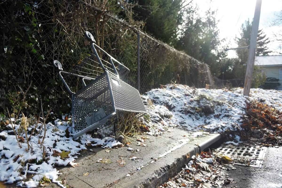 An overturned shopping cart and piles of leaves sit by a "No Dumping" sign at the corner of Charles Street and Dean Street in Stamford, Conn. Tuesday, Dec. 3, 2019. Neighbors are trying to get the city to clean up all the illegal dumping on their streets, but the city says it has to stop cleanup this time of year because crews are collecting leaves and plowing and sanding the streets.