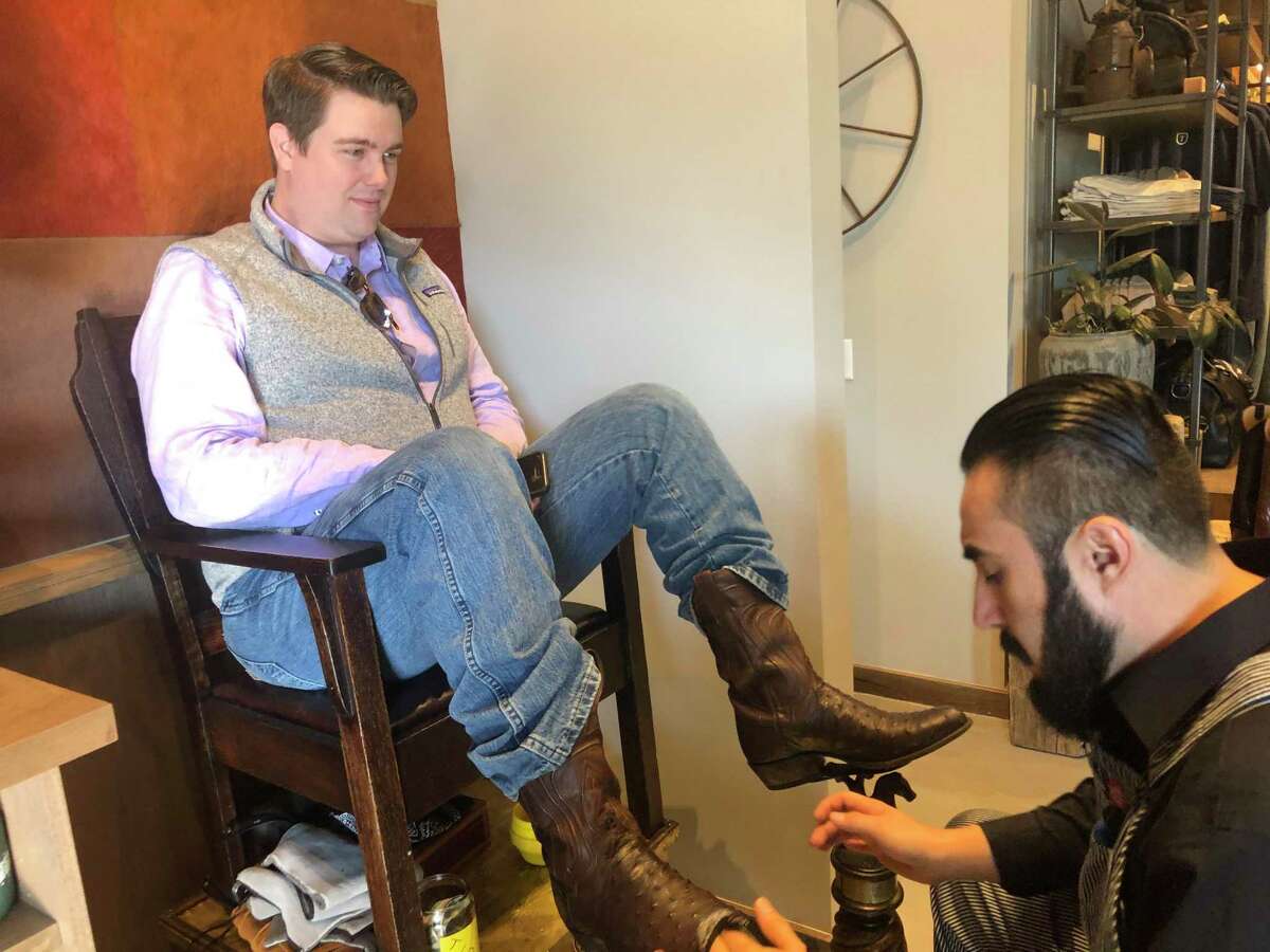 Boot Shiner Saul Amador talks with customer Chris Kannady as he works at the Tecovas grand opening in Rice Village on Saturday, Dec. 7. The Austin-based western retailer sells handcrafted boots and other leather goods.