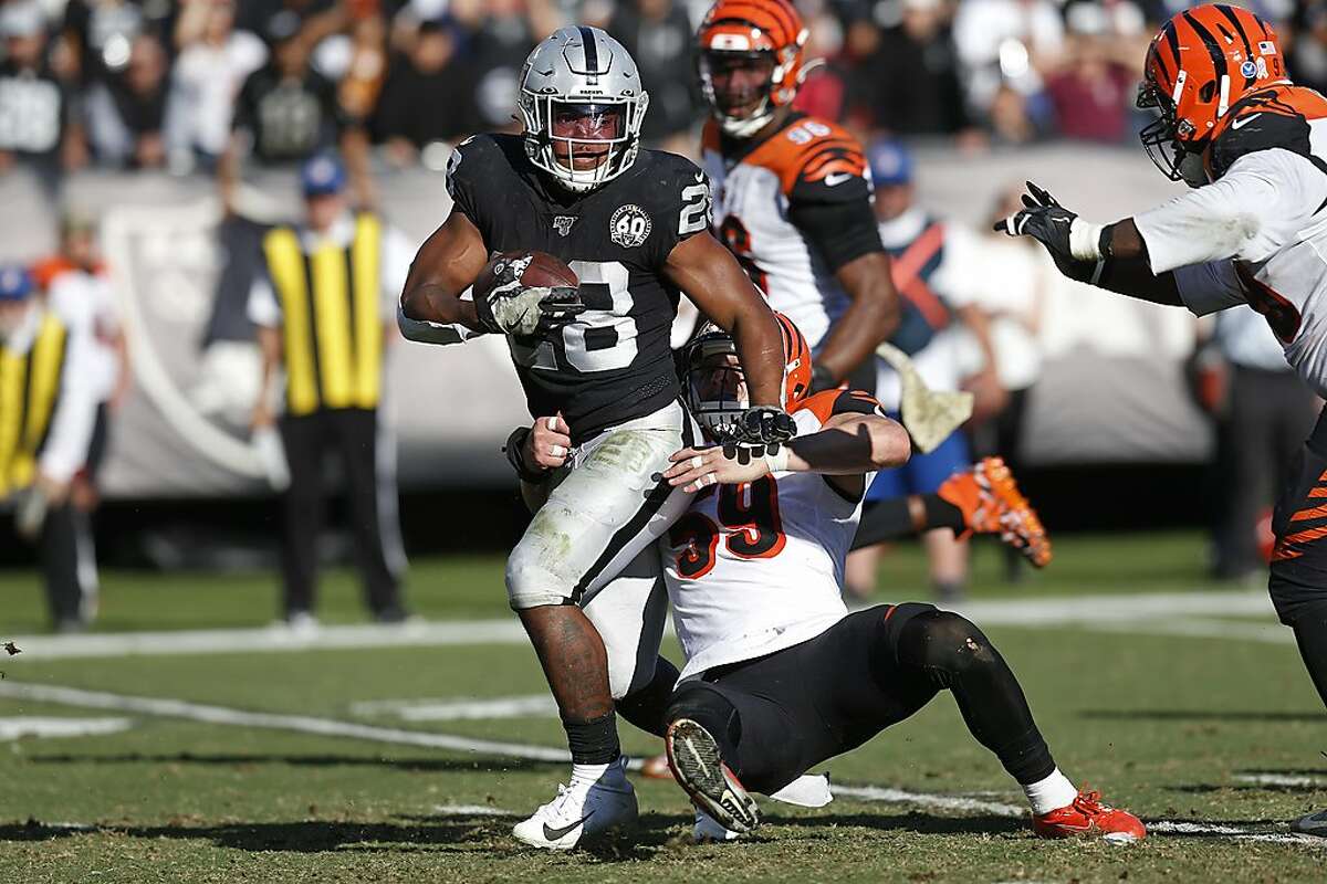 FILE - In this Nov. 17, 2019, file photo, Oakland Raiders running back Josh Jacobs runs with the ball away from Cincinnati Bengals outside linebacker Nick Vigil (59) during the first half of an NFL football game, in Oakland, Calif. Thanks to having three first-round picks last year because of trades that sent established stars Khalil Mack and Amari Cooper away, the Raiders have gotten more touchdowns (14), sacks (11), yards rushing (1,079) and receptions (82) than any other class of rookies this season thanks in large part to strong performances from first-round running back Josh Jacobs and fourth-round defensive end Maxx Crosby. (AP Photo/D. Ross Cameron, File)