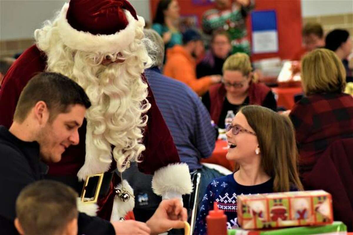 Caleb Lutz, of Glen Carbon, listens in to see what his 9-year-old daughter, Sydney tells Santa her Christmas wishes.
