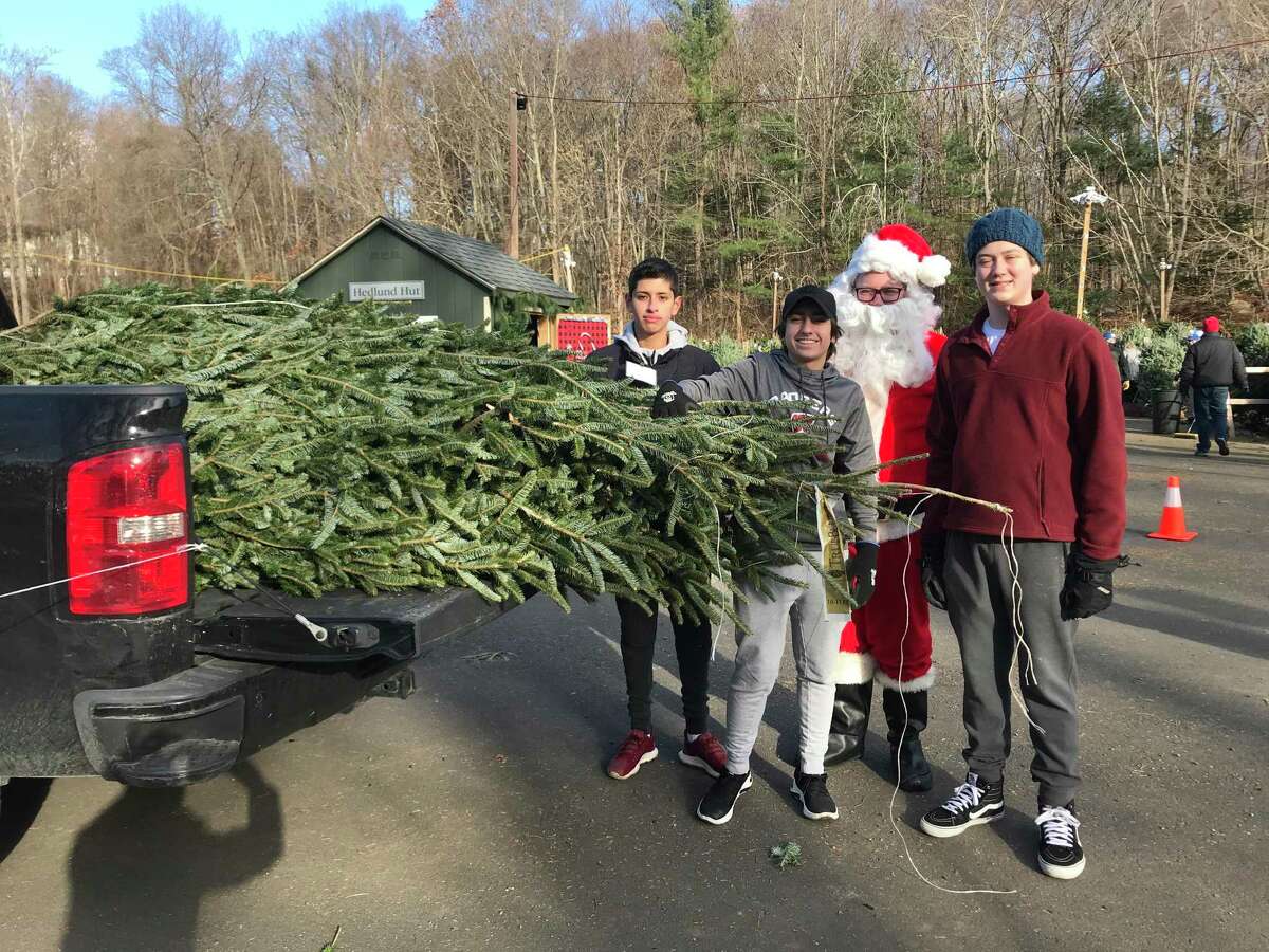 New Canaan High School Service League of Boys (SLOBs) members Ben Apicella, Payton Welch and Johnny Maechling lend Santa a hand at the Exchange Club’s 52nd annual Christmas Tree sale at Kiwanis Park.