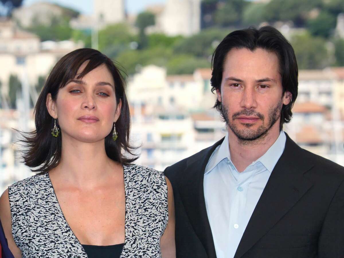 US actor Keanu Reeves and Canadian-born actress Carrie-Anne Moss pose for photographers on a terrace of the Palais des festivals during the photocall for "Matrix Reloaded" directed by the Wachowski brothers during the 56th Cannes film festival on 15 May 2003. - Sci-fi franchise "The Matrix" will return for a fourth film with Keanu Reeves reprising his role as kung fu-kicking, shades-wearing hero Neo, studio Warner Bros said Tuesday. Lana Wachowski will helm the project, returning to write, direct and produce the latest installment of the hugely popular series about humans trapped in a virtual reality by machines, which has netted more than $1.6 billion worldwide. (Photo by FRANCOIS GUILLOT / AFP) / ALTERNATIVE CROP (Photo credit should read FRANCOIS GUILLOT/AFP via Getty Images)