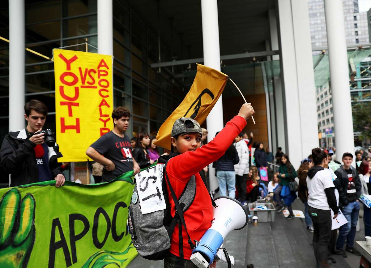 Iman, 11, who didn't provide a last name, with Earth Guardians Bay Area Crew, waves a flag bearing the extinction symbol as he participates in a climate change protest outside of BlackRock Investments, an action led by youth climate strikers in San Francisco, Calif., on Friday, December 6, 2019. Hundreds of local middle and high school students along with adult allies demanded immediate action to address the climate crisis and insisted that BlackRock divest from fossil fuels.