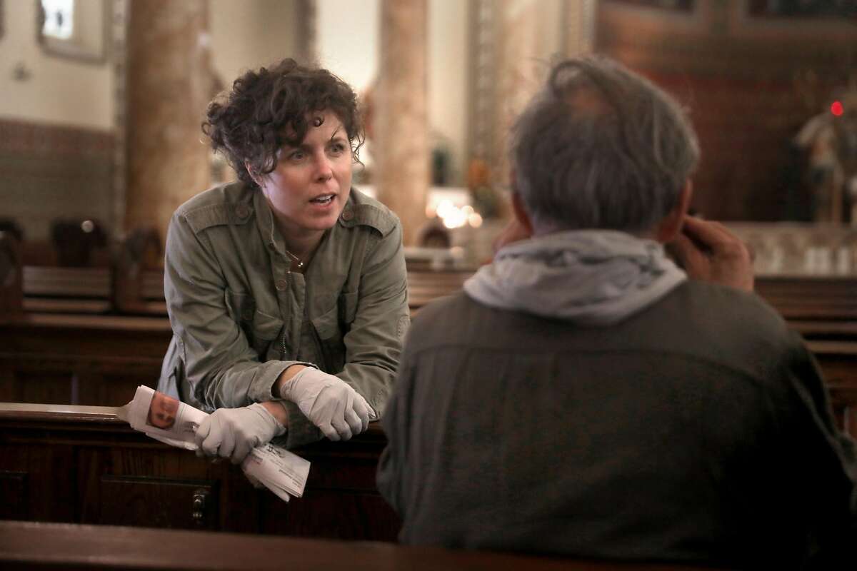 Executive director Shannon Eizenga (left) of the Gubbio Project talks with someone just getting up from sleeping in one of the pews at St. Boniface Church on Wednesday, Nov. 13, 2019, in San Francisco, Calif. Project Gubbio was founded in 2004 by community activist Father Louis Vitale.