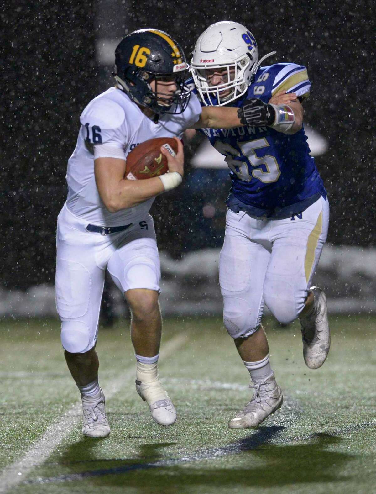 Newtown's James Knox (65) catches Simsbury quarterback Aiden Boeshans (16) in the backfield during the first half of the Class LL State Football semifinal game between No 4 Simsbury and No. 1 Newtown high schools, Monday December 9, 2019, at Newtown High School, Newtown, Conn.