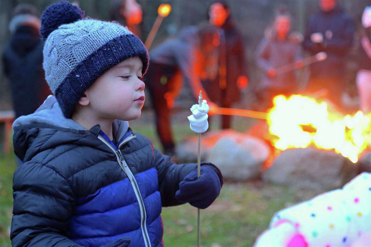 James Shorten, 3, of Westport, enjoys a marshmallow by the fire at the tree lighting event at the Wakeman Town Farm on Dec. 6, 2019, in Westport.
