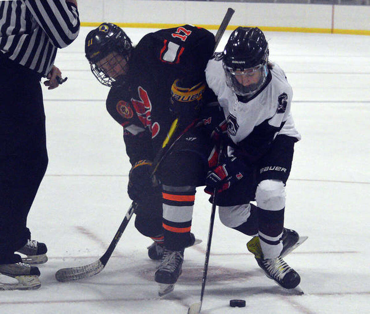 Edwardsville’s Carter Zimmer, left, battles for the puck during Monday’s game against Rockwood Summit at the Kennedy Recreation Complex.