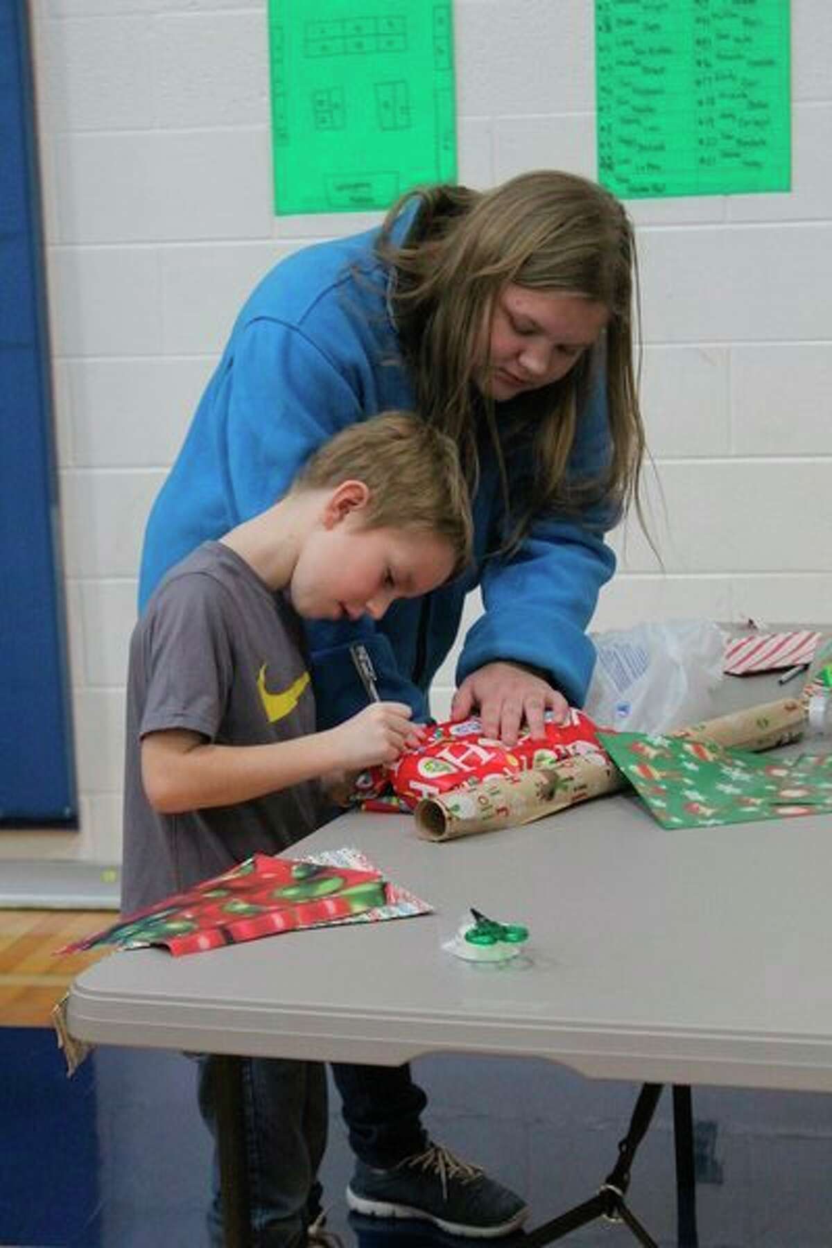 In one area of the gym, students gathered to get help writing their names on gift tags. (Pioneer photo/Catherine Sweeney)