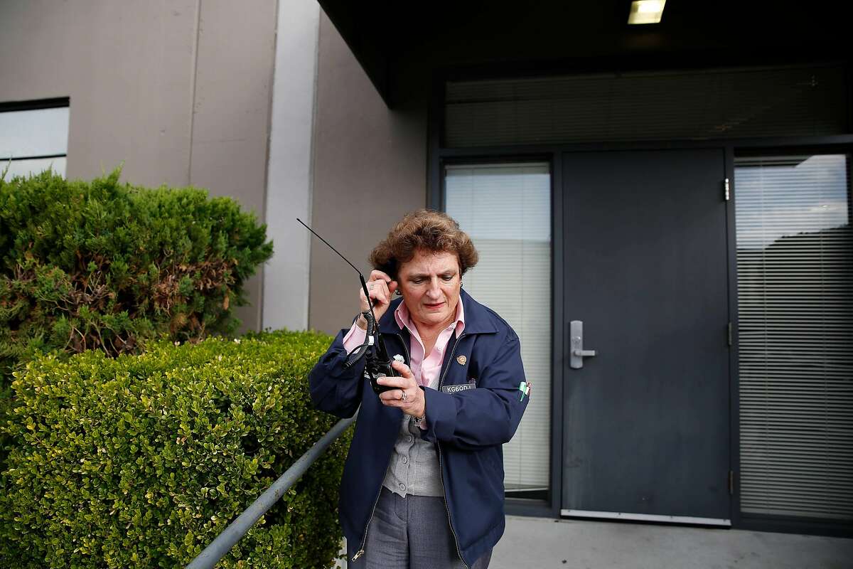 Cathy Peterson, membership lead and volunteer Auxiliary Communications Service, holds her ear to her handy talkie after noticing a delay while waiting to hear the noon warning sirens sound on Tuesday, December 10, 2019 in San Francisco, Calif. San Francisco warning sirens will do their last blaring on Tuesday December 10, 2019 before a two-year overhaul of the system.