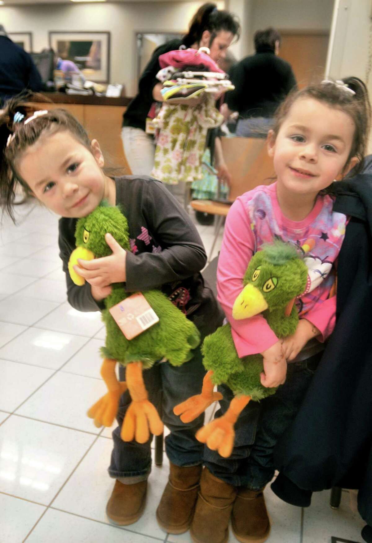 Twins Angie and Christine Goraieb, 4, of East Haven, hold stuffed toys while their mother, Cindy Perillo, organizes their purchases at the Kohl's department store in Branford during the East Haven Rotary Club’s 12th annual "Clothe the Children" campaign in 2012.