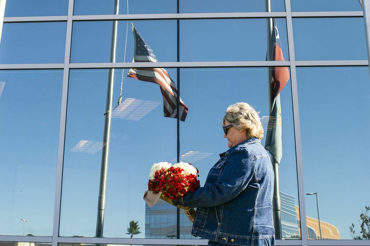 Robin Cortinas, of Taylor Lake, lays flowers at the American Flag at half staff in front of the building that houses the Nassau Bay City Hall and police department, Wednesday, Dec. 11, 2019. Nassau Bay Police Department Sgt. Kaila Sullivan was struck and killed by a car Tuesday night while trying to arrest a suspect. Law enforcement officials are currently searching for the suspect, 21-year-old Tavores Dewayne Henderson, who is now charged with felony murder.