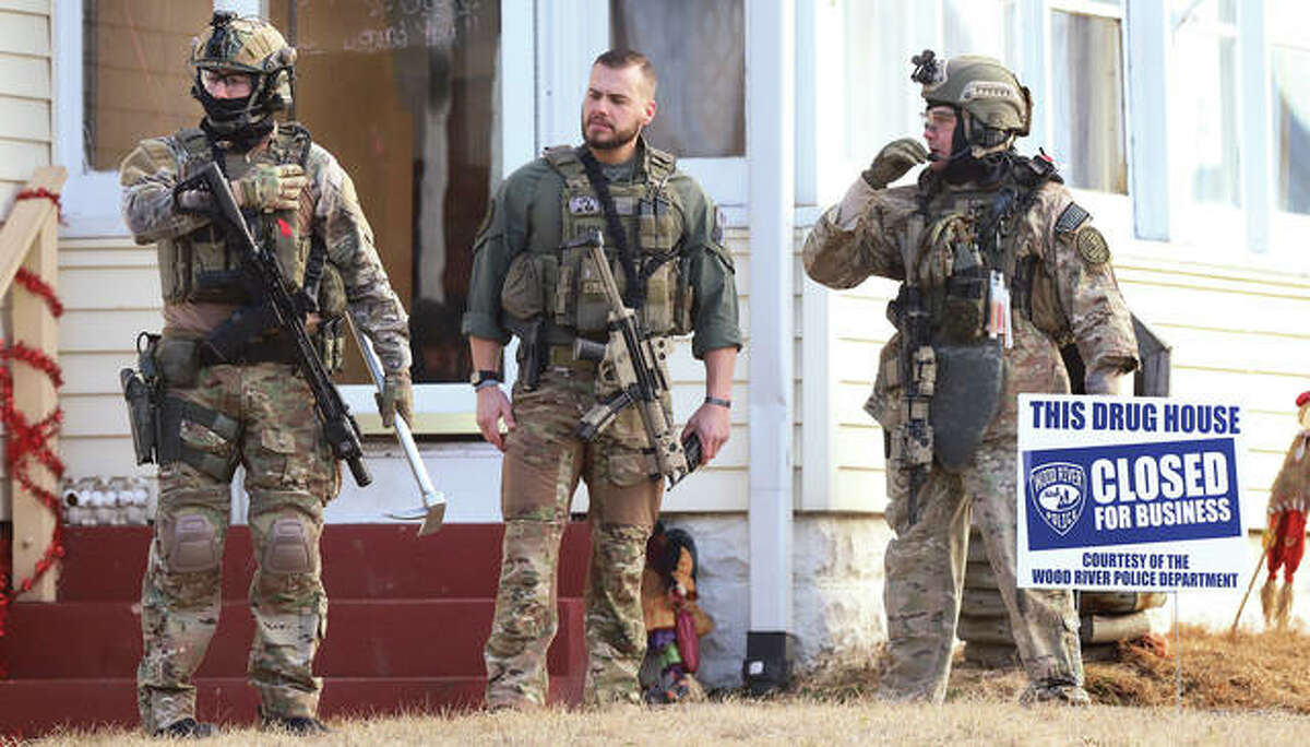 ILEAS members, heavily armed, stand in the front yard after police posted a sign in the front yard declaring the “Drug house closed for business.”