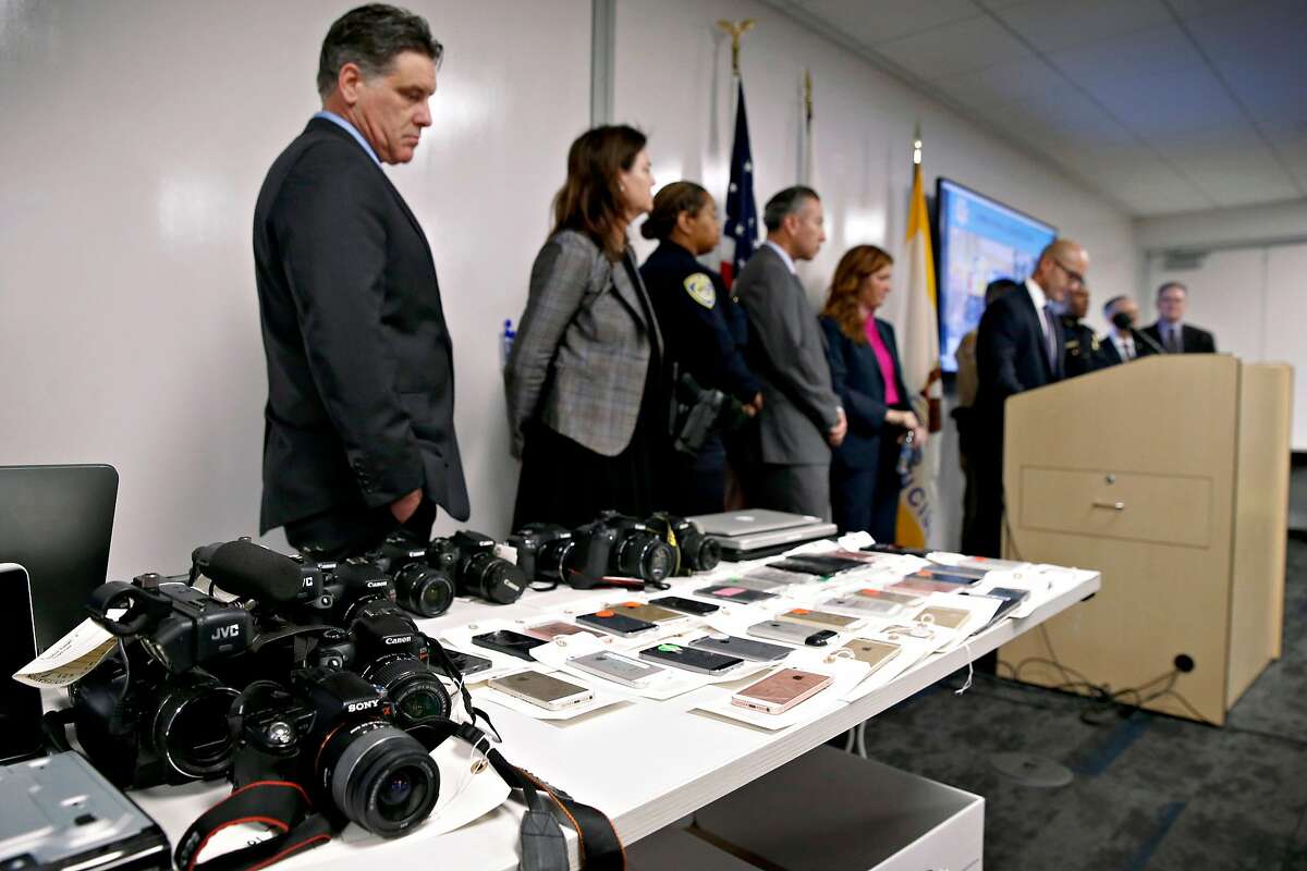 Sean Connolly (left), a prosecutor with the District Attorney's office, stands near recovered electronic equipment displayed during a news conference in San Francisco, Calif. on Thursday, Dec. 12, 2019 to announce the seizure of more than $2 million of stolen property following a multi-agency investigation called Operation Focus Lens. Connolly leads the group in the DA�s office that led the operation.