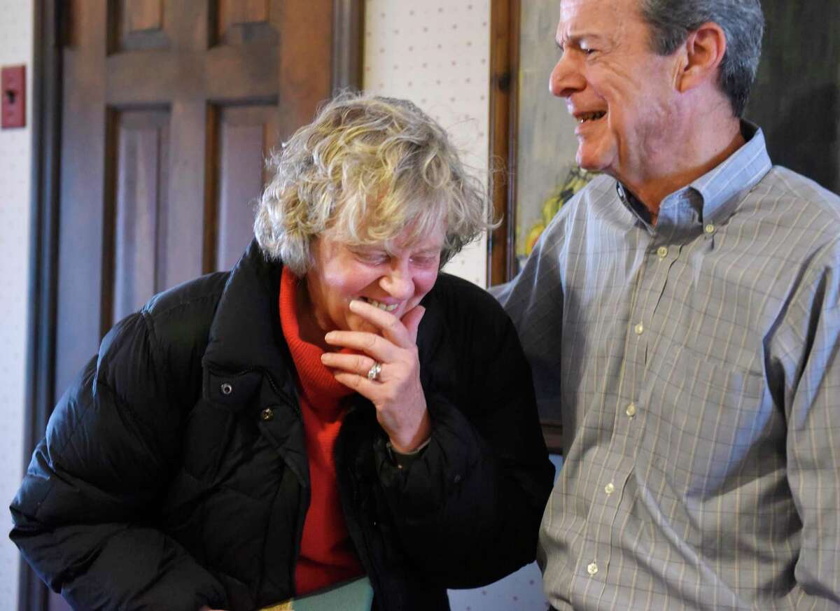 Cathy Ostuw, co-founder of Building One Community, smiles beside her husband, Rich Ostuw, after being surprised at a friend's home in Stamford, Conn. to learn that she is this year's Stamford Citizen of the Year winner on Thursday, Dec. 12, 2019. Ostuw was heading to her weekly Scrabble game with friends when Mayor David Martin and dozens of friends and colleagues suprised her with the honor, which is sponsored by Post 142 of the Jewish War Veterans of the United States. Building One Community's mission is to advance the successful integration of immigrants and their families.