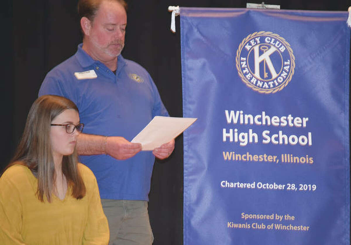 Key Club President Millie Lashmett (left) listens Tuesday as Winchester Kiwanis Club President Chuck Frost speaks during the Key Club’s induction ceremony at Winchester High School.
