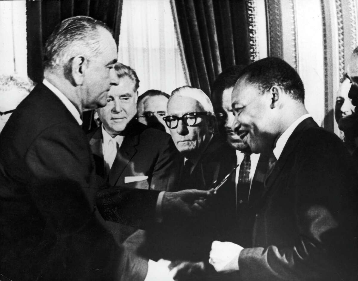 U.S. President Lyndon B. Johnson hands a pen to civil rights leader Rev. Martin Luther King Jr. during the the signing of the voting rights act as officials look on behind them on Aug. 6, 1965. The U.S. House has just passed an update to the act, and Republicans in the Senate should take it up, too.