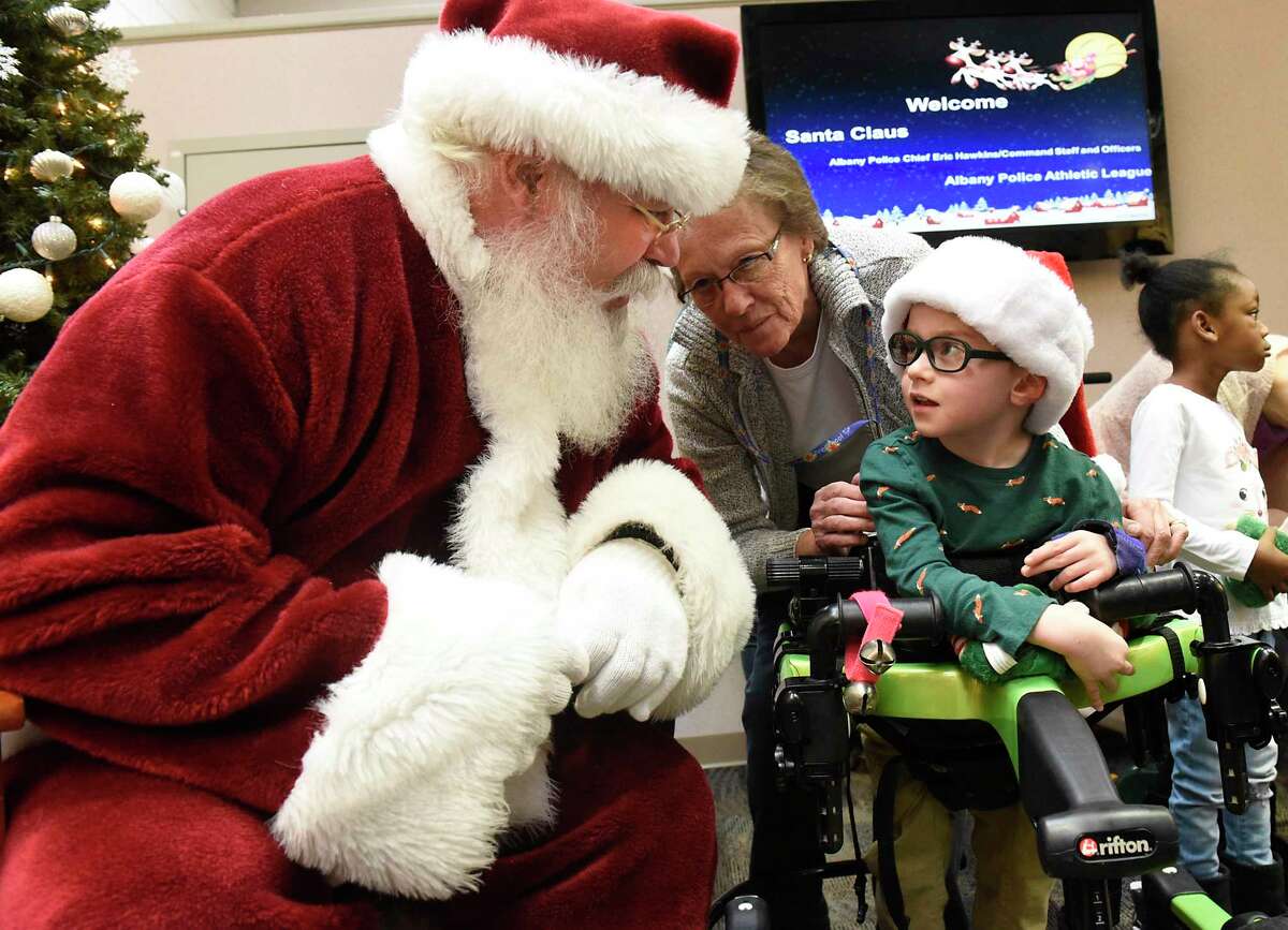 With his teacher Kathleen Kennedy behind him, Killian Polario, 4, visits with Santa Claus at Center for Disability Services on Friday, Dec. 13, 2019 in Albany, N.Y. Police Athletic League (PAL) members distributed presents to children at the center. (Lori Van Buren/Times Union)
