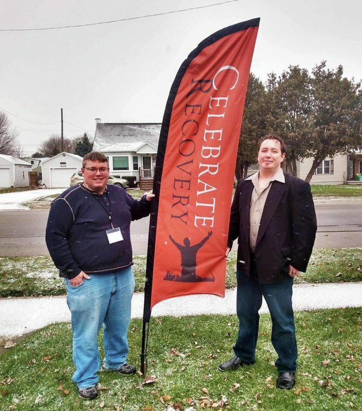 Pastor Ean Green, left, stands by the Celebrate Recovery banner with ministry leader Dave Ross, right. (Sara Eisinger/Huron Daily Tribune)