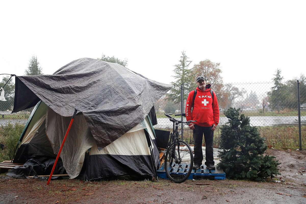 Mike Westfall, who is a resident of the homeless encampment along the Joe Rodota Trail, stands for a portrait with his tent, bicycle and an artificial Christmas tree on Wednesday, December 11, 2019 in Santa Rosa, Calif.