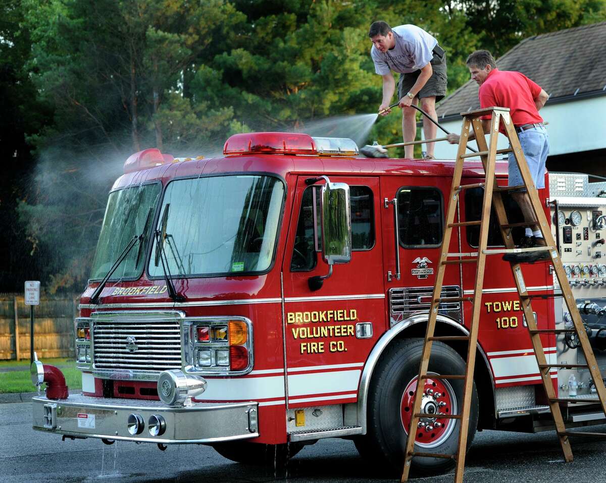 Robert Weinstein, left, and Glenn Martone, firefighters with the Brookfield Volunteer Fire Co., wash down the ladder truck Monday evening, July 30, 2012. Once a month, the company's regular meetings includes an apparatus check. Cleaning the equipment is often on the agenda.