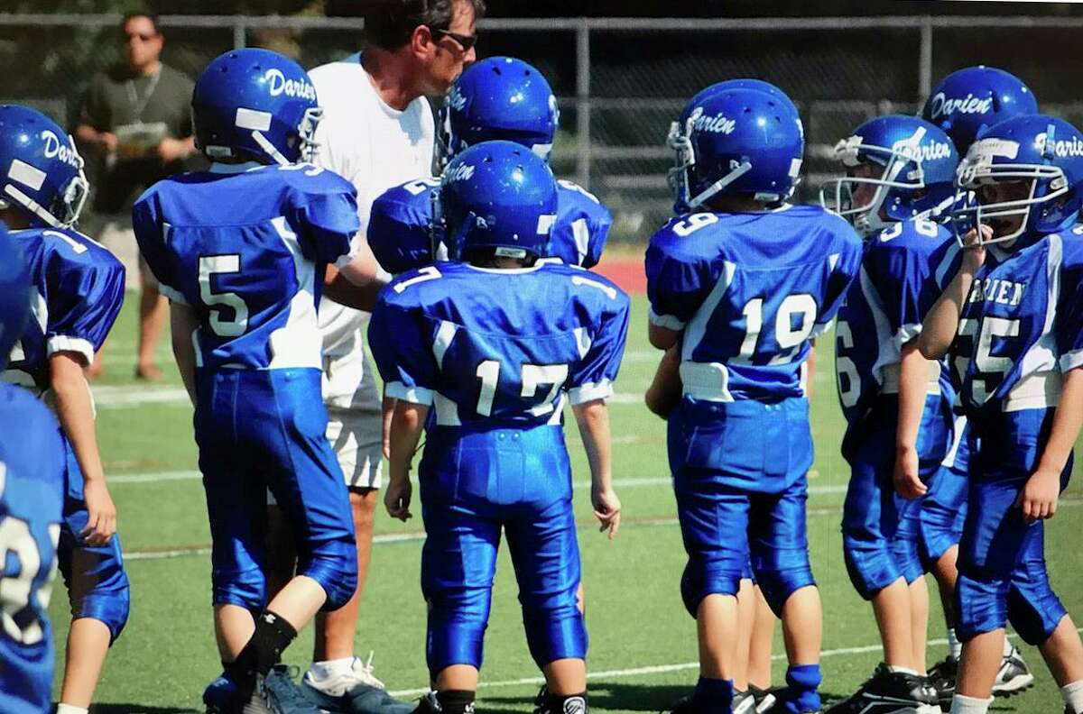 Darien High School football coach Rob Trifone works with the Darien Junior Football League's third-grade team during the 2010 season. Trifone has coached that group of players for the past 10 seasons, and many are seniors on his 2019 Blue Wave varsity team.