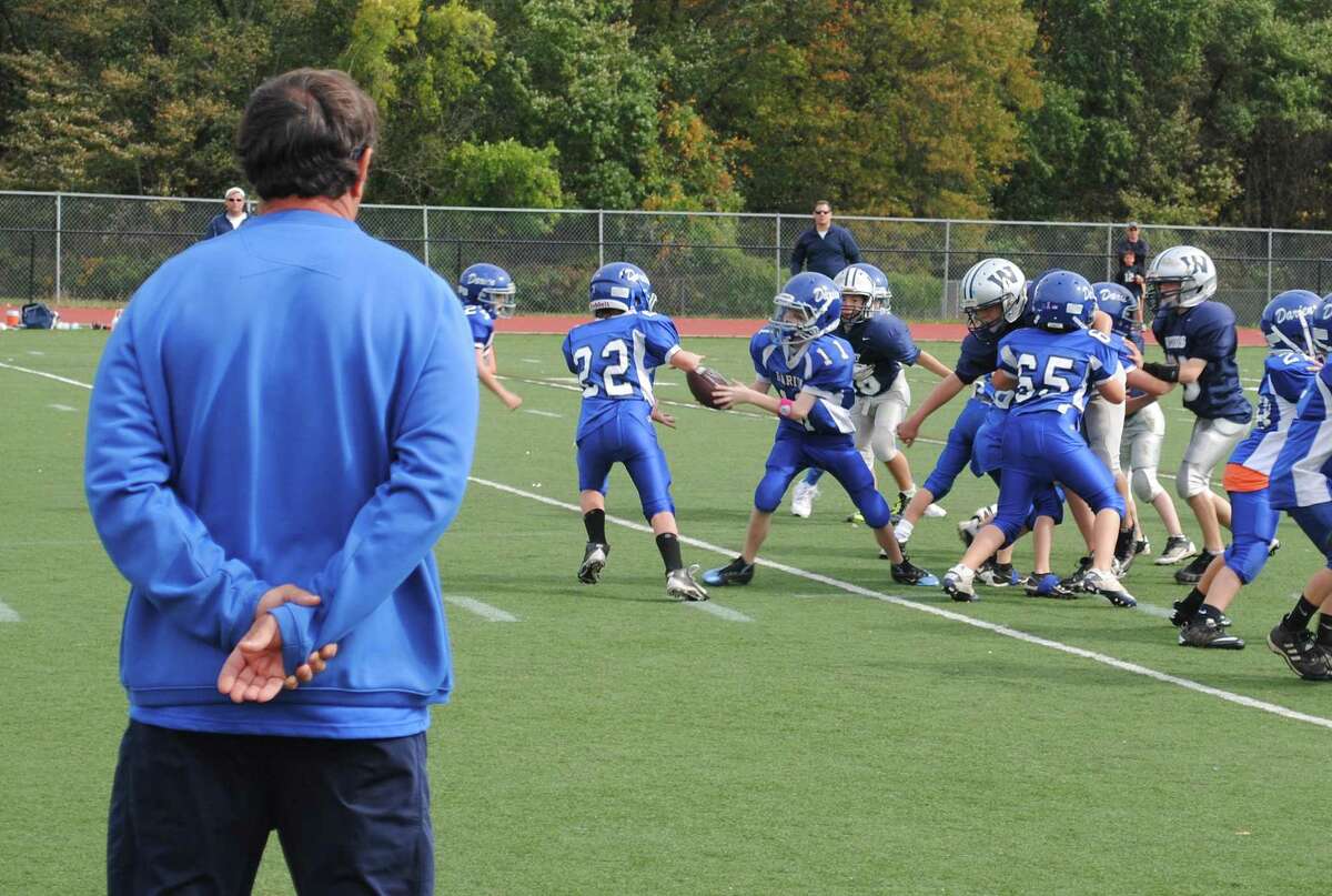 Rob Trifone watches the Darien Junior Football League third-grade team during a game in 2010. Trifone has coached that group of players for the past 10 seasons, and many are seniors on his 2019 Blue Wave varsity team.