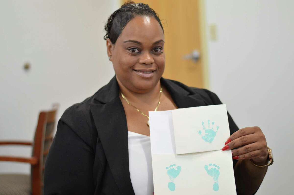 DCF social worker Tameka Saunders holding baby Leon’s hand and footprints.