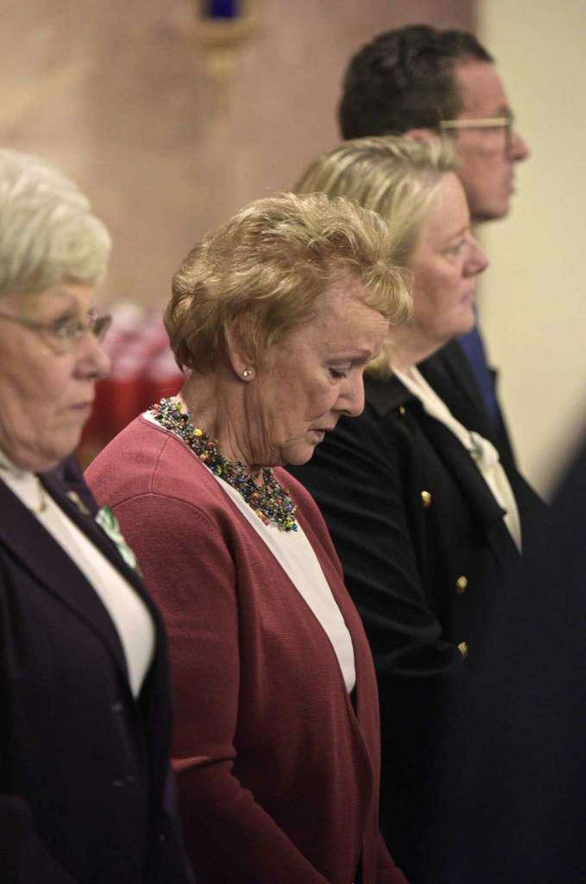 File Photo: Former Newtown First Selectman Pat llodra, center, bows her head as St. Rose of Lima, in Newtown, welcomed Bishop Frank Caggiano for a special mass on De. 14, 2017. The service was held on the fifth anniversary of the day 20 first-graders and six educators were killed at Sandy Hook Elementary School. With Llodra are former Lt. Governor Nancy Lyman, left, and former Gov. Dannel Malloy and his wife Cathy Malloy.
