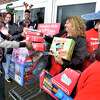 Hamden, Connecticut - Saturday, December 14, 2019: WalMart employee Riketta Jones, of New Haven, left, gives a personal toy donation to Christine Buechette, program director of the Hamden Community Services, Hamden Police Department/Youth Center, second from right, for the The Hamden Kids Holiday Toy Drive at the Hamden Mart in Hamden Saturday during a fundraising collaboration by the Hamden Community Services, Hamden Police Department/Youth Center, Hamden Volunteer Fire Fighters, Quinnipiac University and Albertus Magnus College.