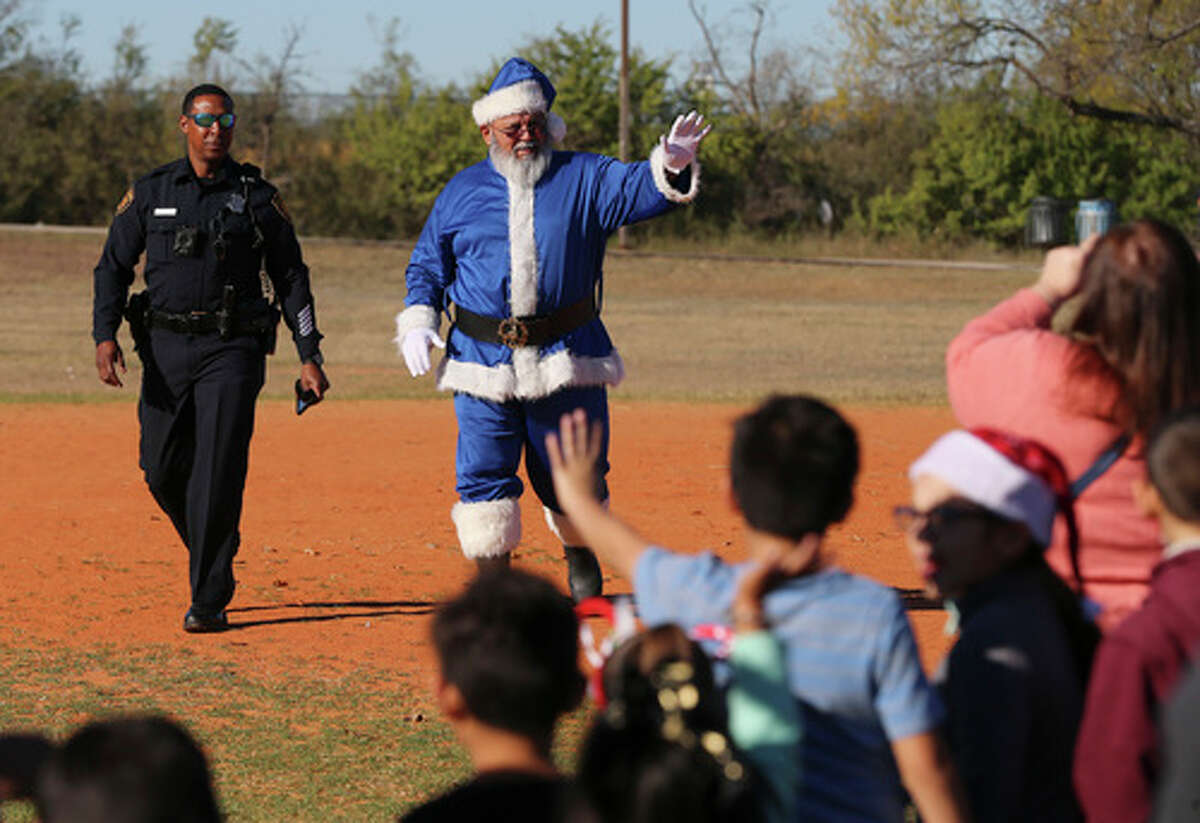 SAPD's Blue Santa waves to children after arriving by helicopter as Southside residents celebrate the holidays at a gathering at Miller's Pond Park on Saturday, Dec. 14, 2019. The event included entertainment, music, food booths and vendors. This is the 19th year for the event that includes a parade and toy give away hosted by the Blue Santa Program, a nonprofit organization created by the San Antonio Police Department. The highlight of the day was when boys and girls went down a basketball court length row of over 2,000 toys of which they could pick one gift for themselves. The program gets their toys from local toy drives, sponsors and vendors of the annual celebration.