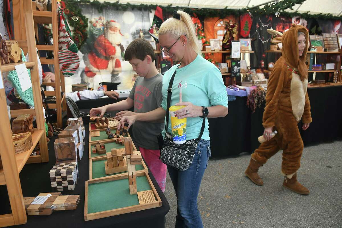 Melissa Bjorgaard, left, and her son Peyton, 10, a 5th grader at Magnolia Inter., Cadence Bidwell, check out the inventory inside the tent of Old Vine Games during Tomball's 12th German Christmas Market at the Tomball Depot on Dec. 14, 2019.