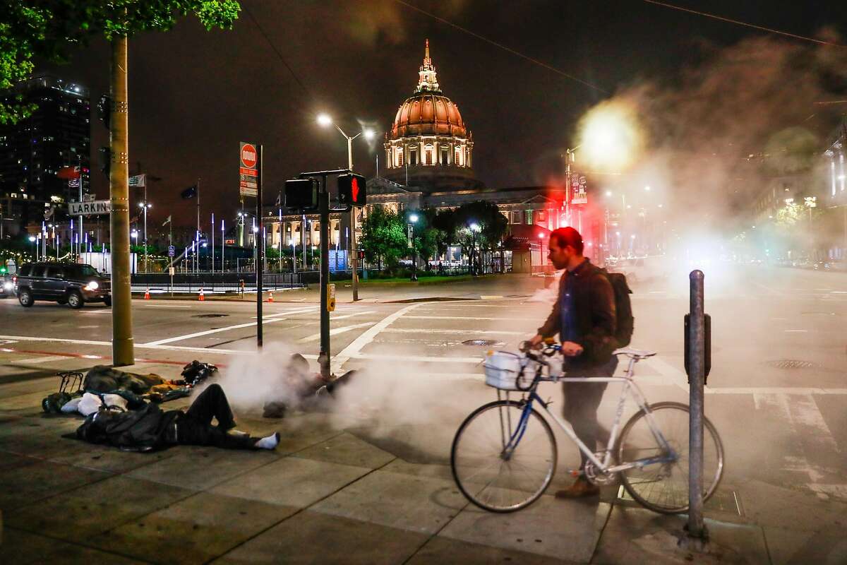 A bicyclist passes by four homeless men sleeping on Larkin Street in San Francisco, California, on Tuesday, June 18, 2019. Photo taken on the corner of Larkin Street and McAllister Street at 11:16pm.