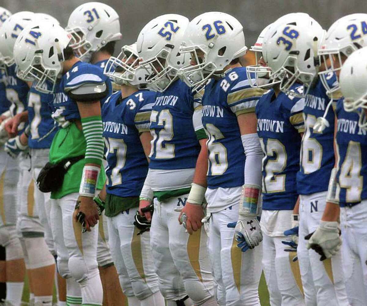 Newtown players hold hands during a moment of silence on the 7th of the Sandy Hook School shooting before the start of state championship football game against Darien in Trumbull, Conn., on Saturday Dec. 14, 2019.