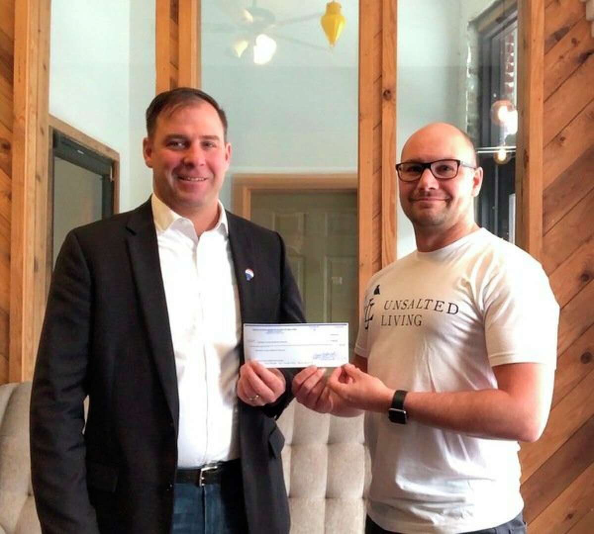 Randy Zakrajsek (left), Manistee County Habitat for Humanity Board President, accepts a donation from Brandon Ball, of Unsalted Living on behalf of the MOM Board of Realtors. (Courtesy photo)